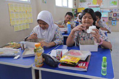 Sejumlah siswa menyantap makanan saat simulasi program Makan Siang Bergizi Gratis di sekolah wilayah Lanud Halim Perdanakusuma di SDS Angkasa 5 Lanud Halim Perdanakusuma, Jakarta, Selasa (26/11/2024). Foto: Ist