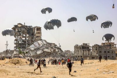 Warga Palestina bergegas paket bantuan kemanusiaan yang dijatuhkan di Jalur Gaza utara pada 23 April 2024. Foto: AFP