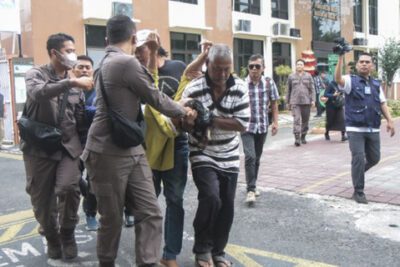Petugas jaksa bersama warga membopong ibu kandung penyandang tunadaksa I Wayan Agus Suartama yang jatuh pingsan usai mendampingi anak kandungnya selaku terdakwa dalam perkara pelecehan seksual sidang perdana di Pengadilan Negeri Mataram, NTB, Kamis. Foto: ANTARA 