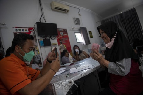 Petugas PT Pos Indonesia (Persero) memotret penerima bantuan langsung tunai (BLT) pengalihan subsidi BBM tahap pertama di Gambir, Jakarta Pusat, Jumat (2/9/2022). Foto: Antara 