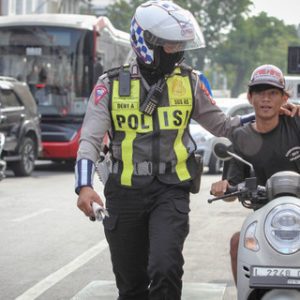 Seorang anggota Satlantas Polrestabes Surabaya menghentikan pengendara motor yang terjaring saat Operasi Patuh Semeru 2024 di Jalan Rajawali, Surabaya, Jawa Timur, Selasa (16/7/2024). Foto: Istimewa