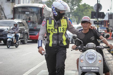 Seorang anggota Satlantas Polrestabes Surabaya menghentikan pengendara motor yang terjaring saat Operasi Patuh Semeru 2024 di Jalan Rajawali, Surabaya, Jawa Timur, Selasa (16/7/2024). Foto: Istimewa