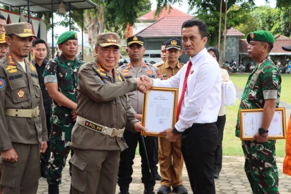 Bupati Tanggamus Berikan Penghargaan kepada 15 Personel Polres Tanggamus Tanggamus - Bupati Tanggamus Drs. H. Mohammad Saleh Asnawi, M.A., M.H.,  memberikan piagam penghargaan kepada 15 personel Polres Tanggamus atas keberhasilan mengungkap kasus pembunuhan pasangan suami istri di Pekon Way Pring, Kecamatan Pugung, dalam waktu kurang dari 1 x 12 jam. Penyerahan piagam penghargaan tersebut dilakukan pada kegiatan Apel Kesiapsiagaan Satuan Perlindungan Masyarakat (Satlinmas) yang digelar di Lapangan Merdeka Kota Agung, Selasa (13/1/2026). Penghargaan diberikan kepada jajaran pimpinan hingga personel lapangan Polres Tanggamus yang dinilai menunjukkan kinerja cepat, profesional, dan responsif dalam menjaga stabilitas keamanan dan ketertiban masyarakat. Adapun 15 personel Polres Tanggamus yang menerima penghargaan tersebut yakni: Kapolres Tanggamus AKBP Rahmad Sujatmiko, S.I.K., M.H., Wakapolres.Tanggamus Kompol Gigih Andri Putranto, S.H., S.I.K., M.H., Kasat Reskrim Polres Tanggamus AKP Khairul Yassin Ariga, S.Kom., M.H., Kapolsek Pugung Ipda Dr. Agus Tri Kurniawan, S.H., M.H., Selain itu personel Tim Tekab 308 Polres Tanggamus dan Polsek Pugung, yaitu Aipda Herwinsyah, S.H., Aipda Frendi Setiawan, S.H., Aipda Sumantri, Aipda Fherli Saputra, Aipda Bobby Noviansyah S., S.E., Aipda Dani Pratomo, Aipda Angga Aradea, Bripka Dedy Syaifuddin, Bripka Anggie Fhariestha, Briptu Sofiansyah, S.H., dan Bripda Muhammad Guma Palanov. Kapolres Tanggamus AKBP Rahmad Sujatmiko menyampaikan terima kasih atas penghargaan yang diberikan oleh Bupati Tanggamus serta dukungan seluruh elemen masyarakat. “Kami mengucapkan terima kasih atas apresiasi Bapak Bupati. Pada awal pengungkapan kasus ini, kami memang minim petunjuk. Namun berkat kerja keras tim serta dukungan informasi dari masyarakat, alhamdulillah kasus tersebut dapat diungkap sebelum 1x12 jam,” kata AKBP Rahmad Sujatmiko. Kapolres juga mengajak masyarakat untuk terus berperan aktif dalam menjaga keamanan dan ketertiban lingkungan. “Kami mengajak masyarakat untuk terus peduli terhadap lingkungan sekitar dan tidak ragu memberikan informasi kepada kepolisian. Dengan sinergi antara masyarakat dan aparat keamanan, situasi kamtibmas yang aman dan kondusif dapat terus terjaga,” pungkasnya. Bupati Tanggamus H. Moh. Saleh Asnawi menyampaikan apresiasi dan rasa bangga atas kinerja jajaran Polress Tanggamus yang dinilai mampu bertindak cepat sehingga kasus pembunuhan tersebut dapat segera terungkap. “Saya memberikan apresiasi setinggi-tingginya kepada Polres Tanggamus yang telah bergerak cepat mengungkap kasus pembunuhan pasangan suami istri di Pekon Way Pring. Keberhasilan ini penting untuk menjaga rasa aman dan mencegah keresahan di tengah masyarakat,” tegas Bupati. Diketahui dalam rangkaian itu, selain kepada jajaran Polres Tanggamus, Bupati juga menyerahkan piagam penghargaan kepada 14 personel Kodim 0424 Tanggamus, 3 personel BPBD Kabupaten Tanggamus, 3 personel Taruna Siaga Bencana (Tagana), serta 6 anggota Tim Vertical Rescue Indonesia atas peran mereka dalam penyelesaian pembangunan Jembatan Gantung Garuda di Pekon Umbar, Kecamatan Kelumbayan. Piagam penghargaan juga diberikan kepada 35 anggota Satlinmas Kabupaten Tanggamus atas dedikasi dan pengabdian mereka yang telah lebih dari 10 tahun menjalankan tugas sebagai anggota Satuan Perlindungan Masyarakat di wilayah masing-masing. (*)